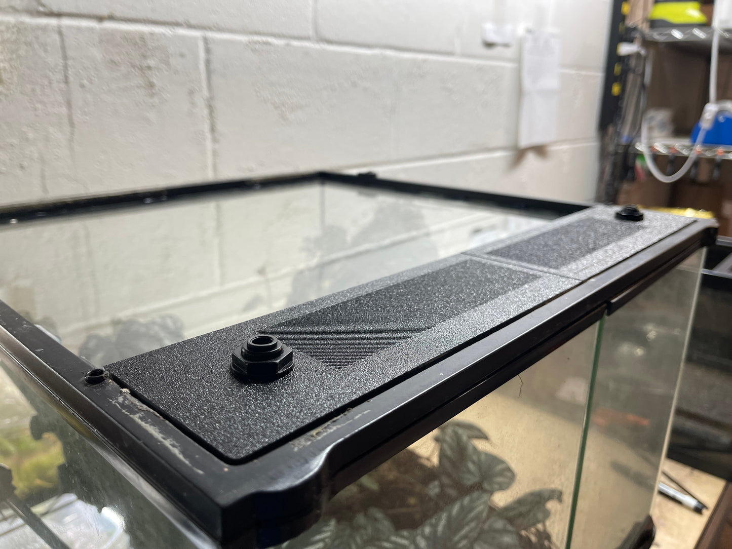 Black aquarium filter on a glass aquarium with a tiled wall background