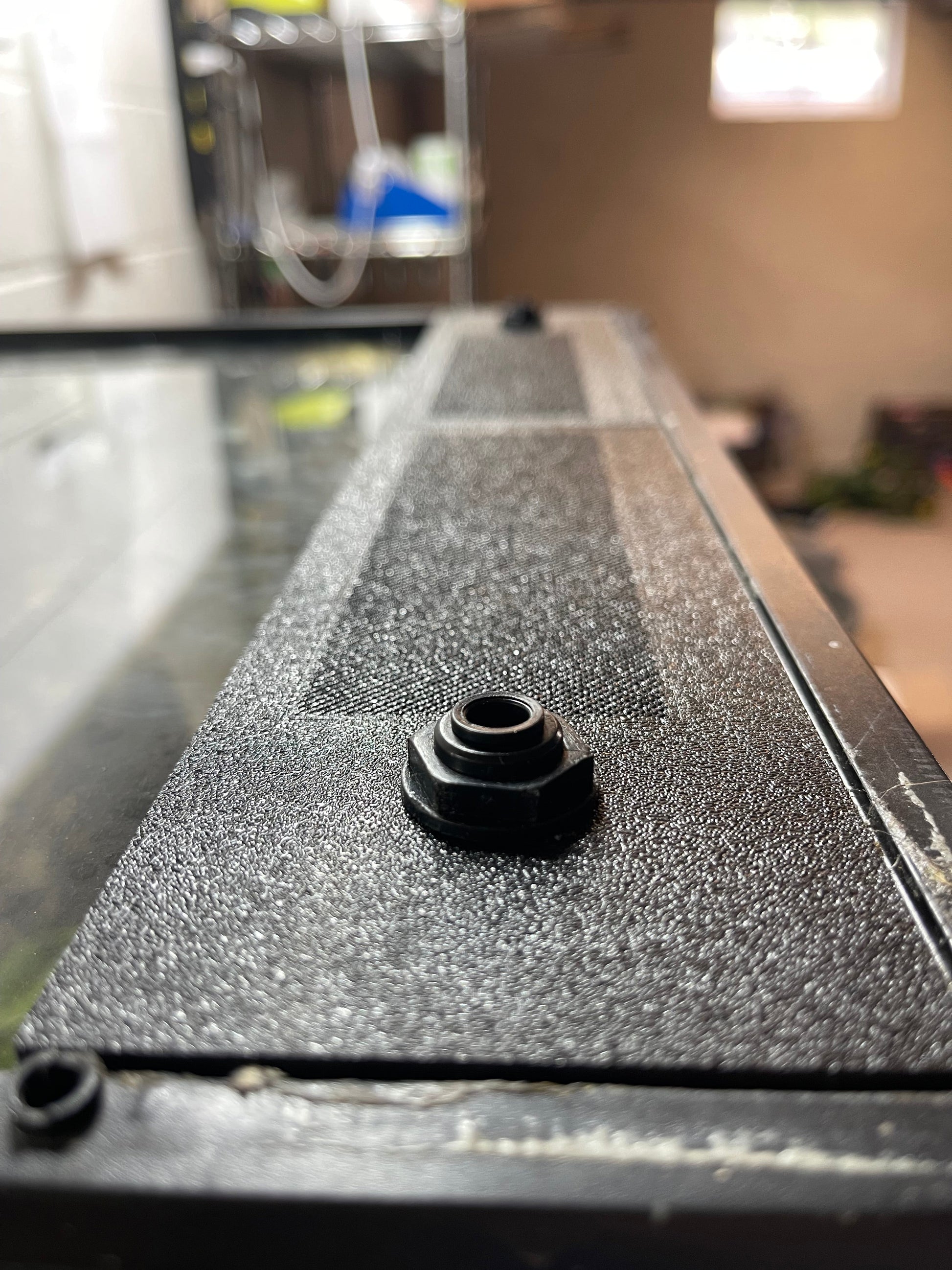 Black hexagonal bolt on a textured black surface with a blurred background