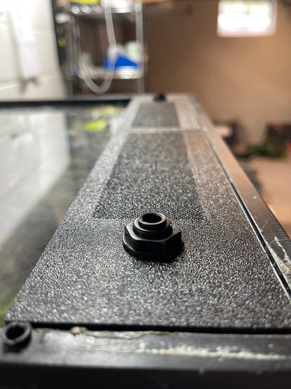 Black hexagonal bolt on a textured black surface with a blurred background