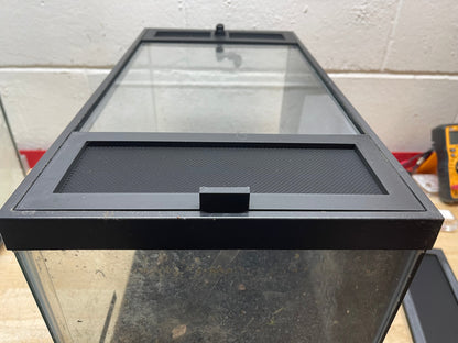 Glass aquarium with black lid on a concrete floor