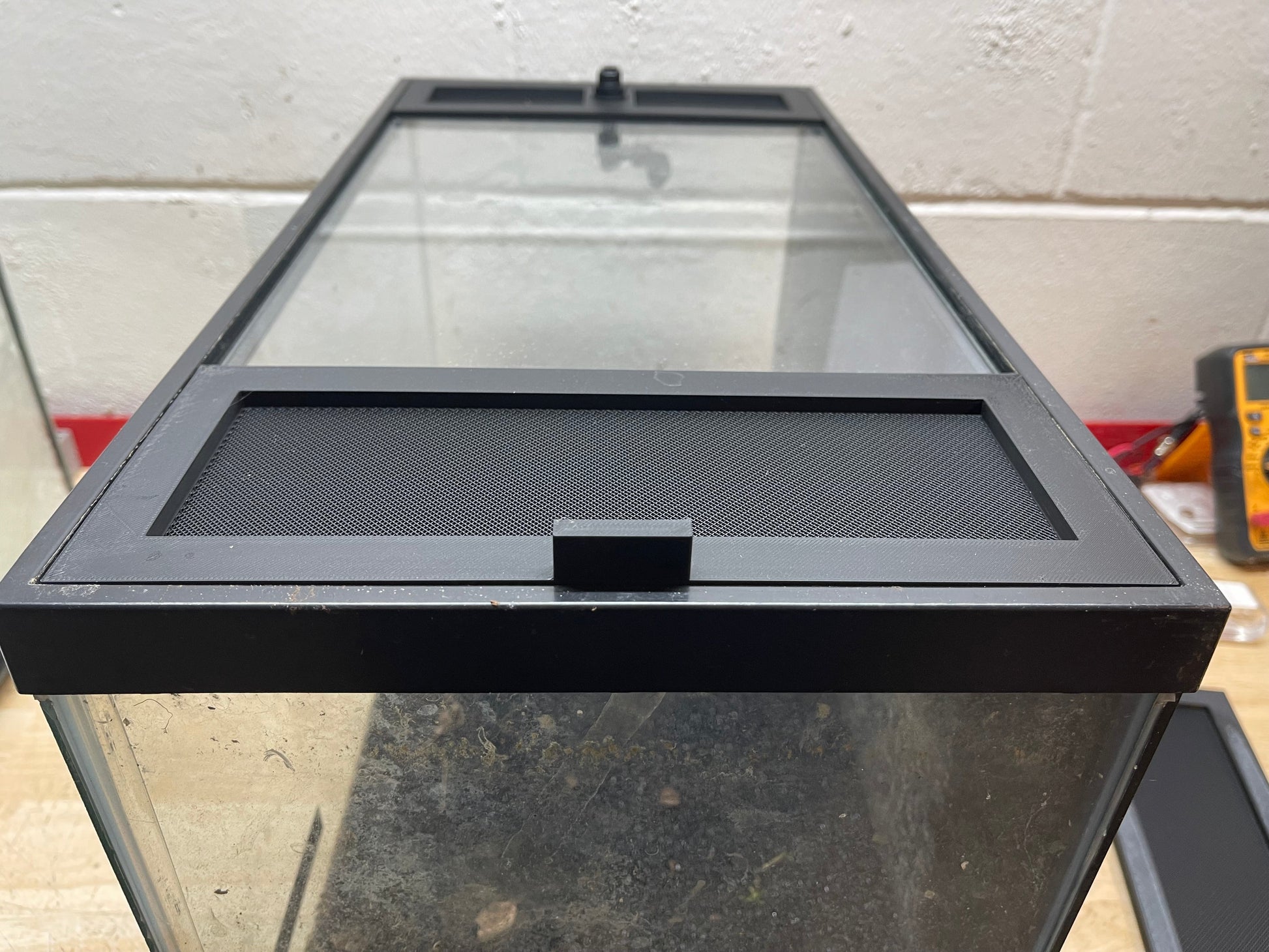 Glass aquarium with black lid on a concrete floor