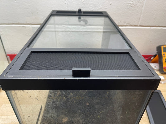 Glass aquarium with black lid on a concrete floor