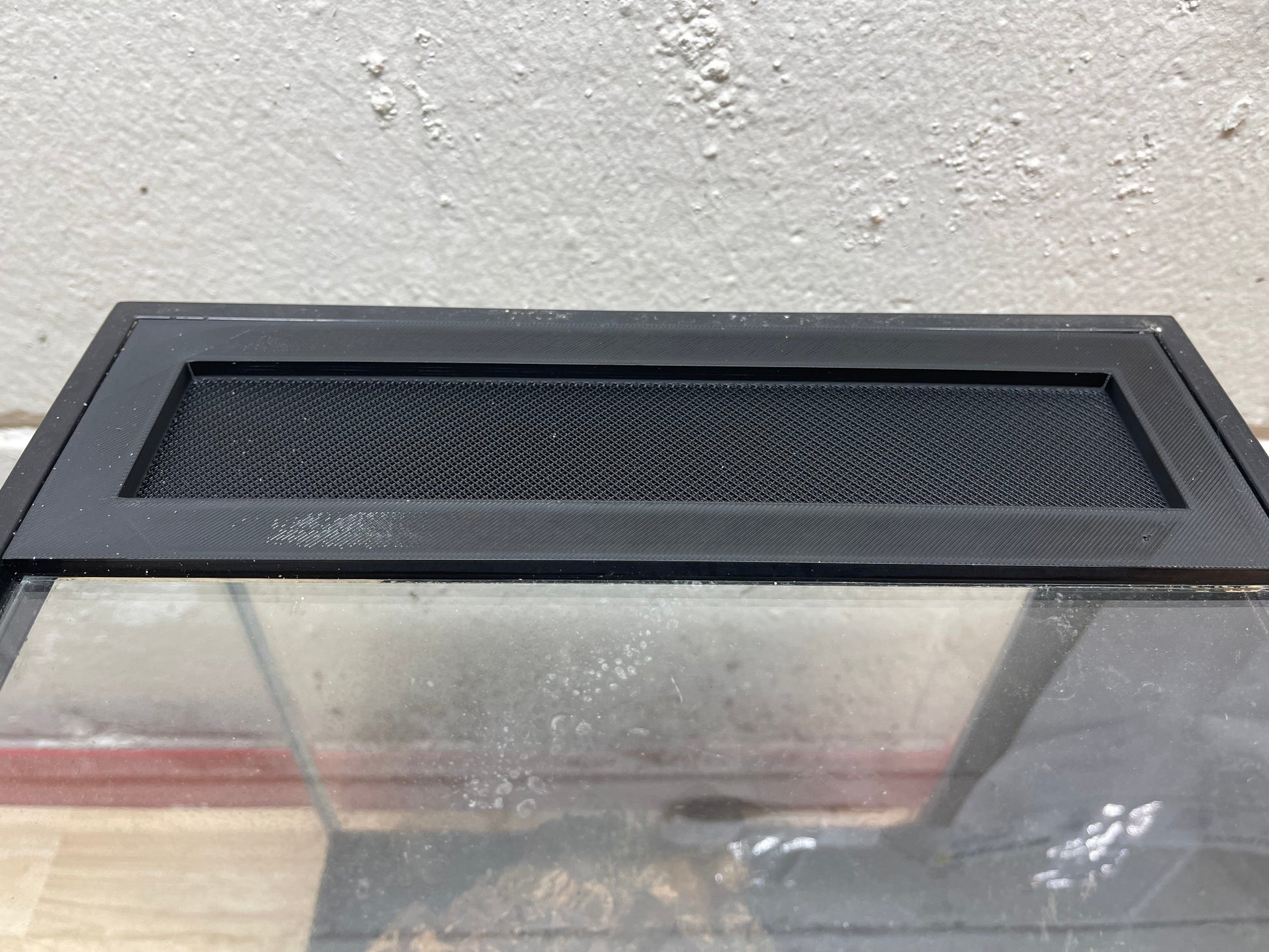 Black metal screen on a glass surface with a concrete wall background