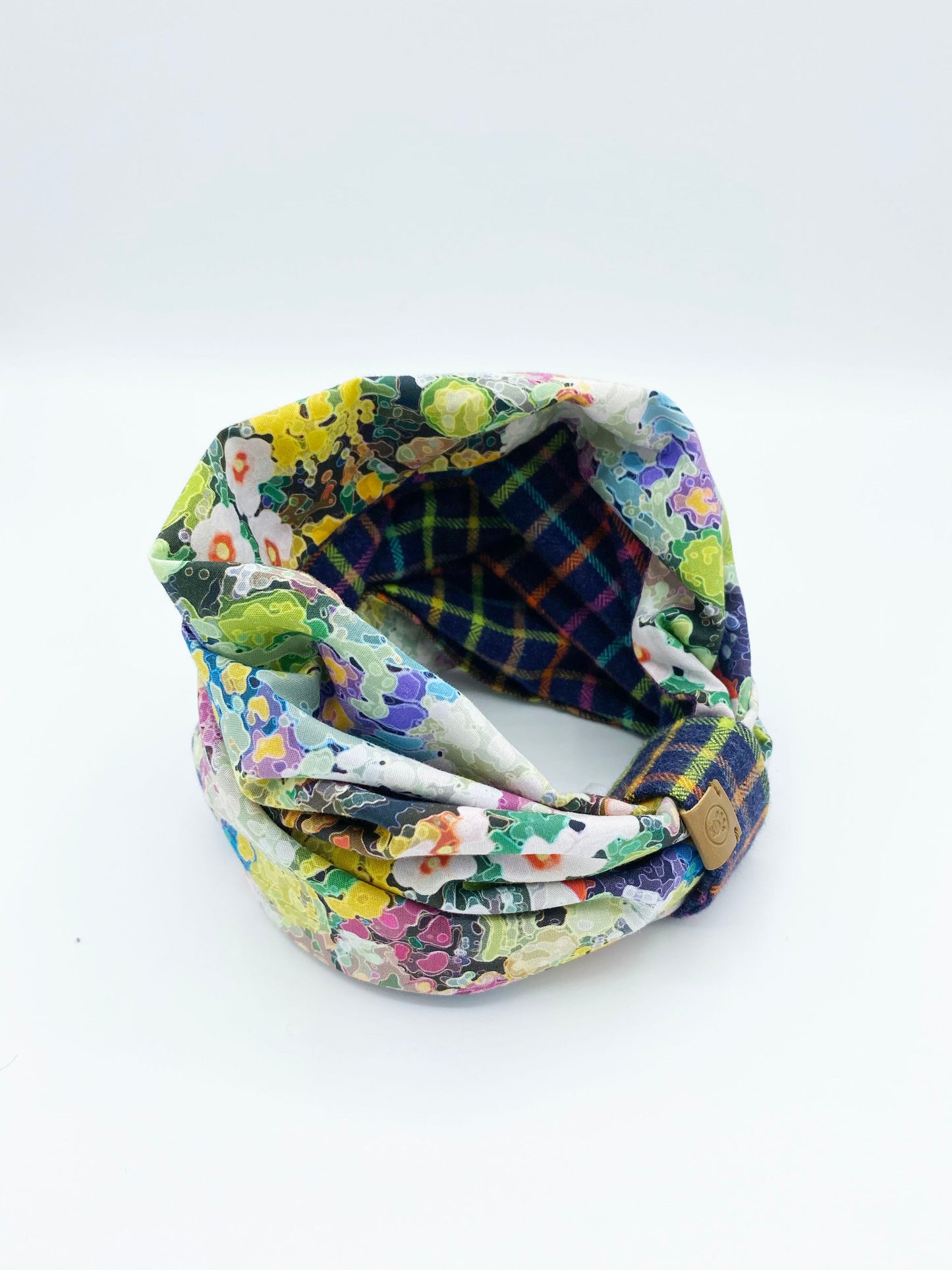 Colorful fabric headband with floral and plaid patterns on a white background