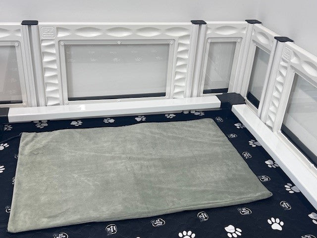 Pet playpen with a gray mat inside on a floor with paw print pattern