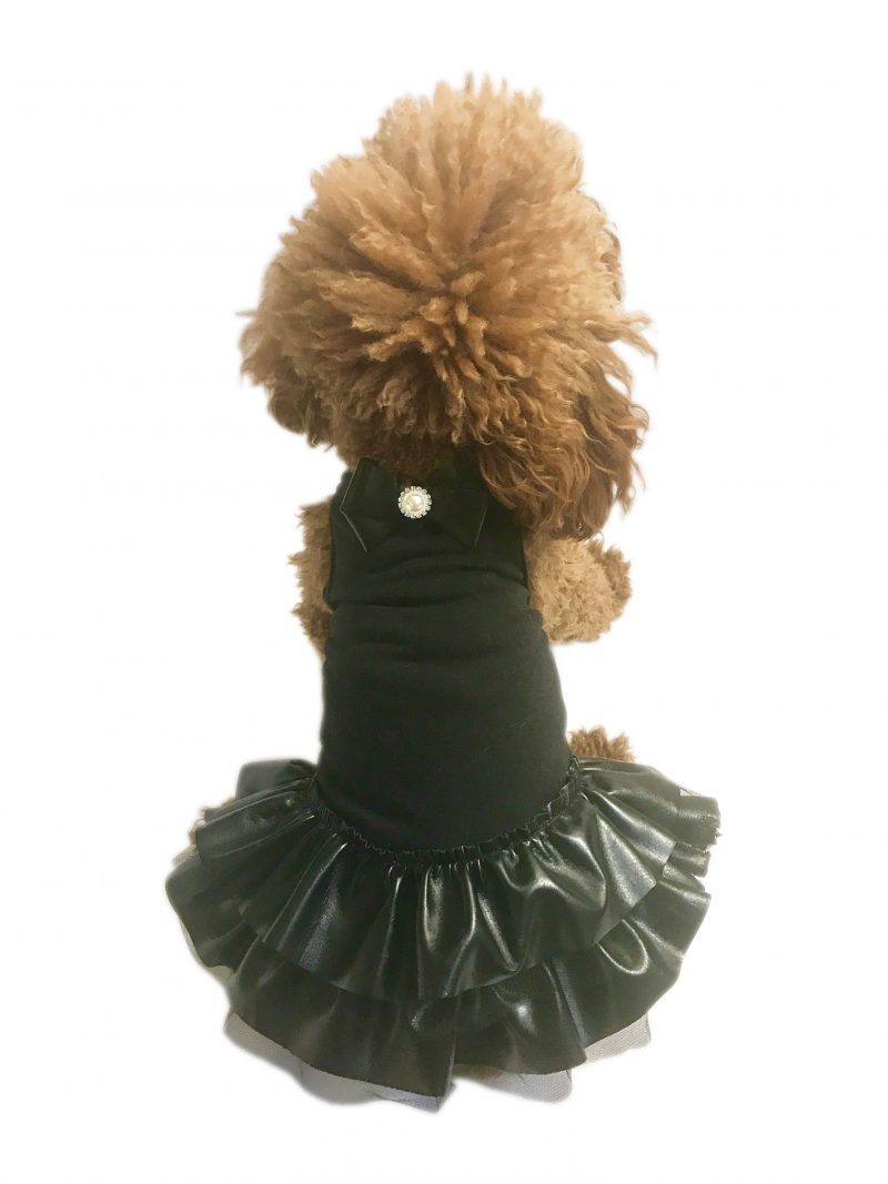 Small dog wearing a black dress with a fluffy white background