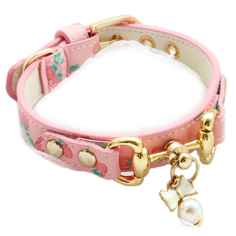 Pink dog collar with gold hardware and decorative charms on a white background
