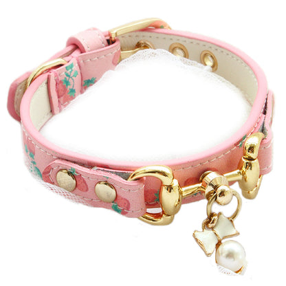 Pink dog collar with gold hardware and decorative charms on a white background