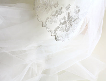 White fabric with floral lace embroidery on a light background