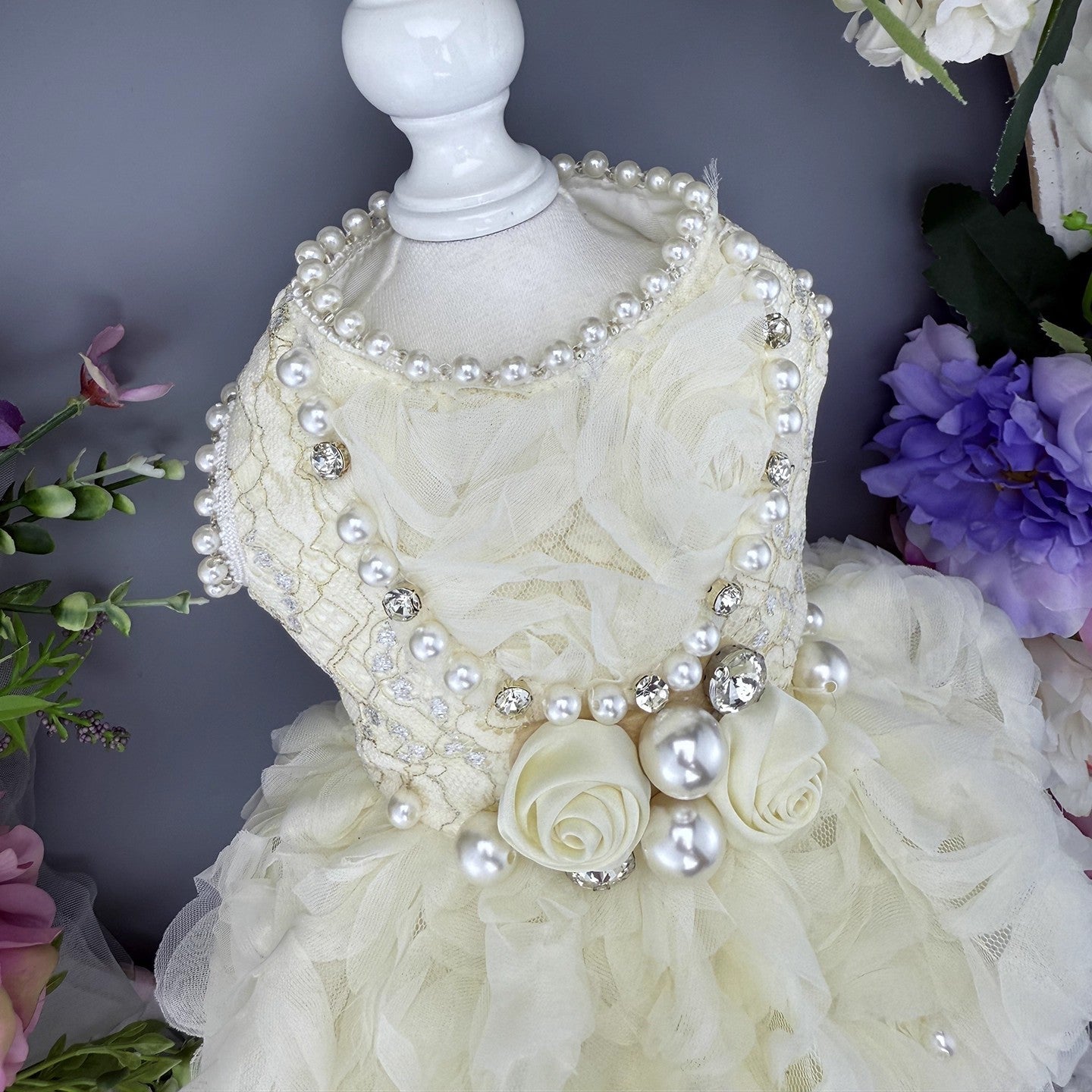 Decorative mannequin head with pearl necklace and floral dress against a floral background