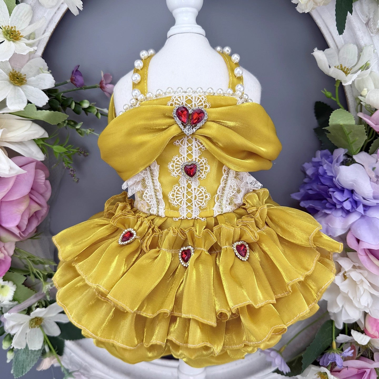 Yellow pet dress with red heart details on a mannequin against a floral background