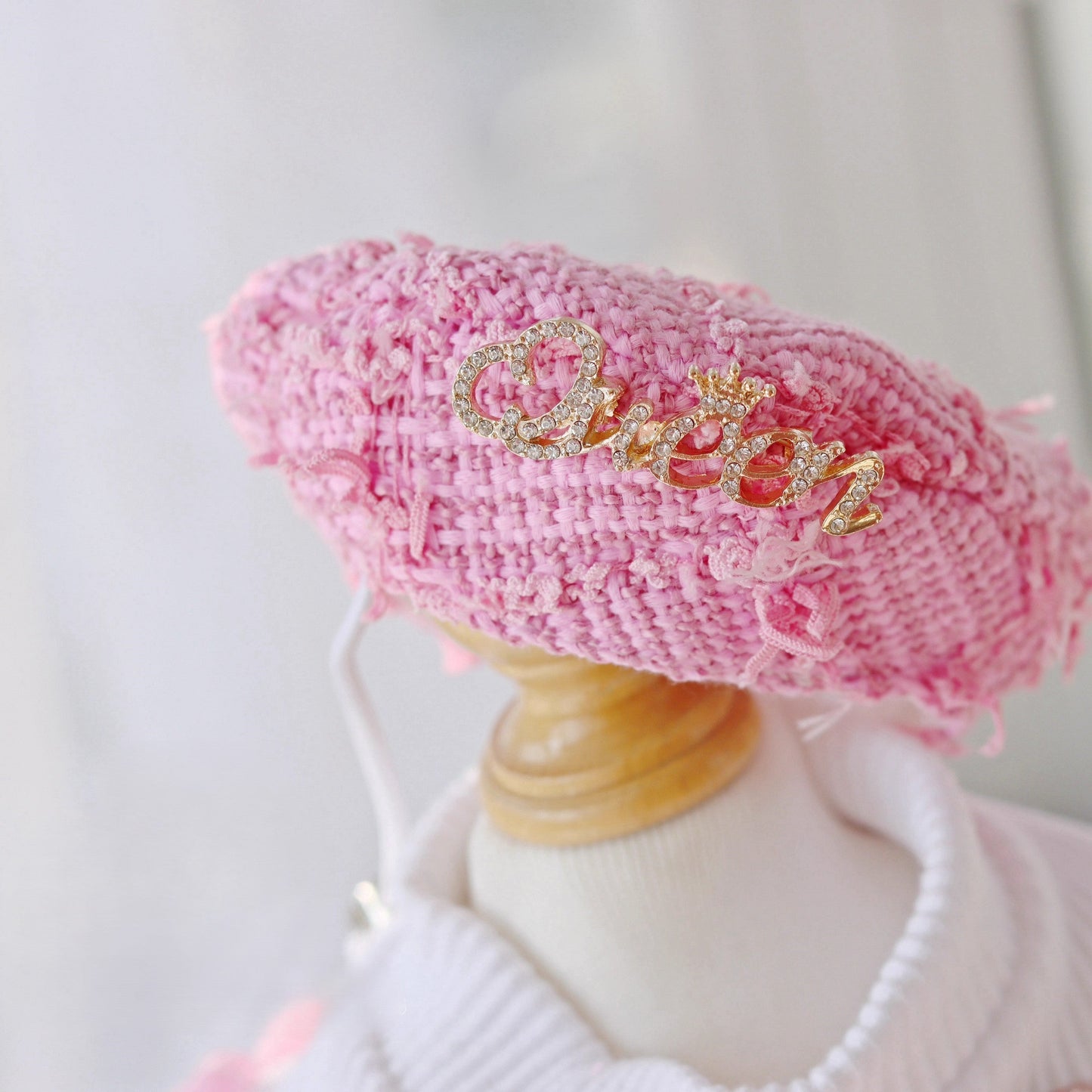 Pink knitted beret with 'Chanel' embroidery on a mannequin head against a light background