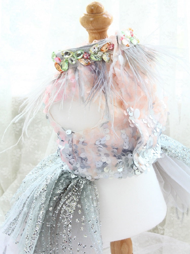 Doll wearing a floral headband and tulle dress with sequins on a white background