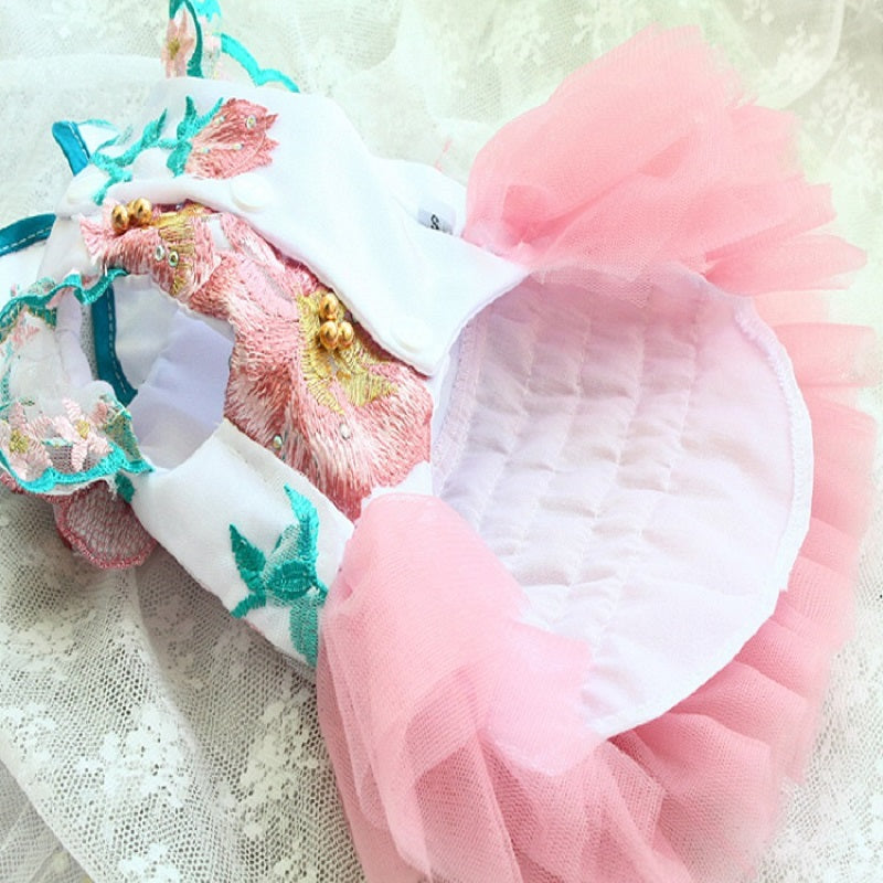 Baby outfit with pink tutu, floral headband, and embroidered top on a textured white background