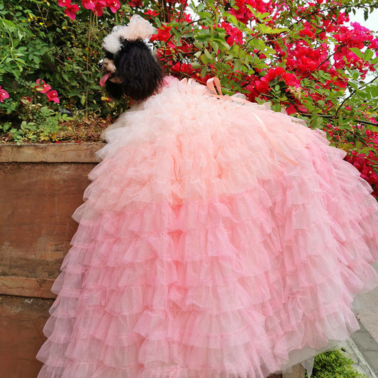Person wearing a pink ruffled dress standing in front of pink flowers