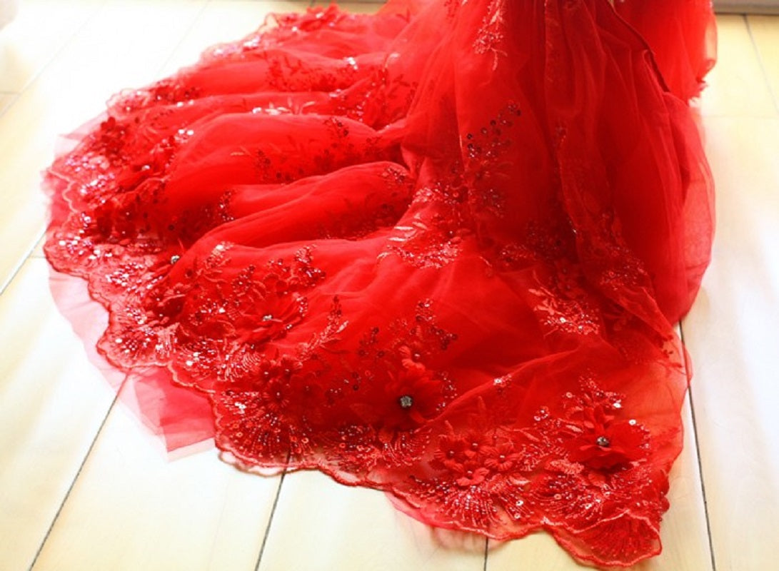 Red wedding dress with lace details on a light wooden floor