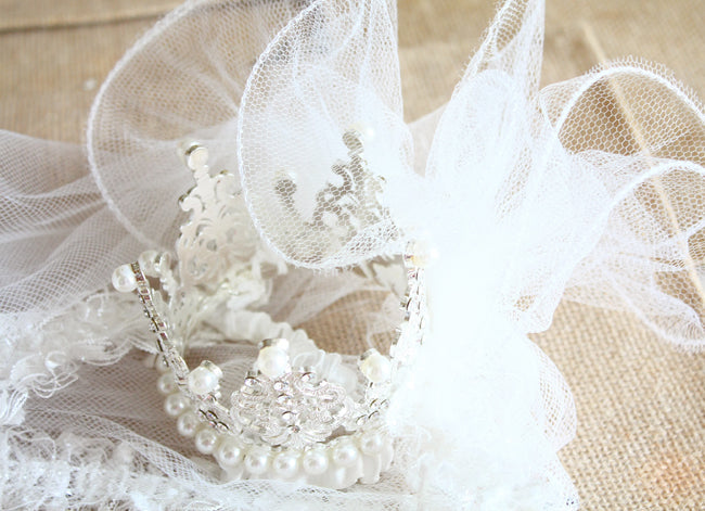Pearl jewelry on a textured beige surface with white lace