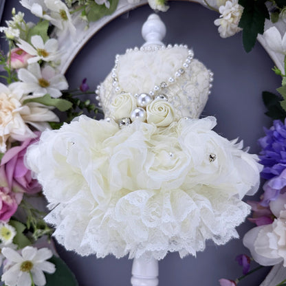 White floral bouquet with pearls against a floral wreath background
