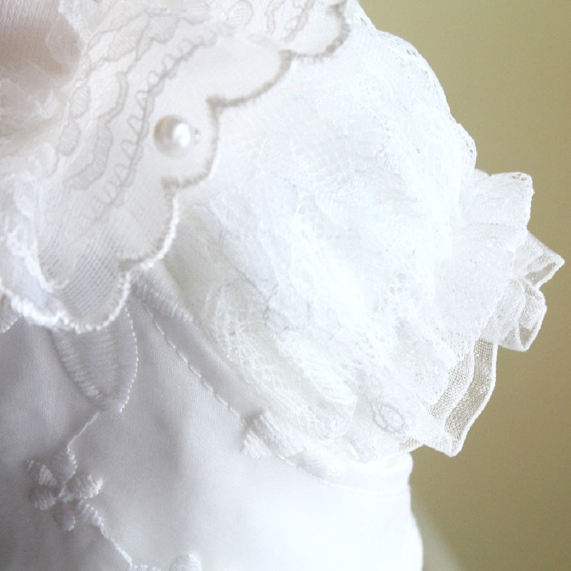 Close-up of a white lace garment with floral details on a beige background