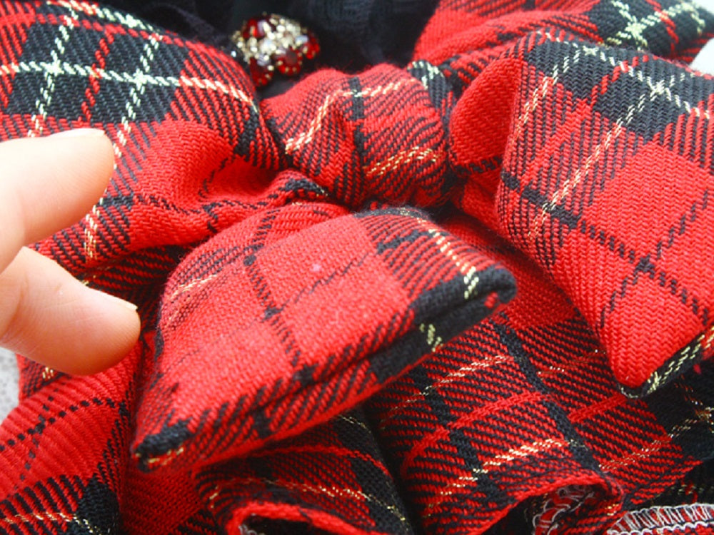 Close-up of red and black plaid fabric with a hand holding it.