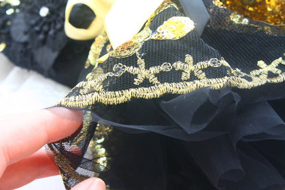 Close-up of black fabric with gold embroidery held by a hand.