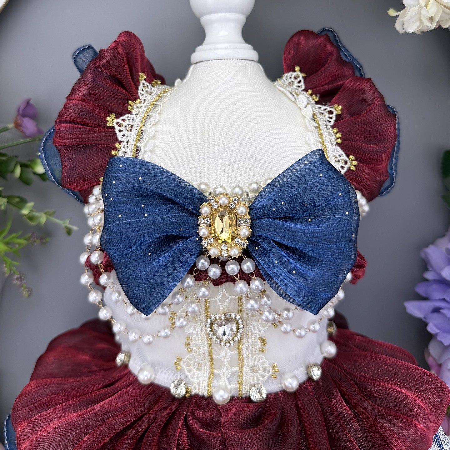 Decorative headpiece with blue bow, red and white accents on a mannequin against a gray background.