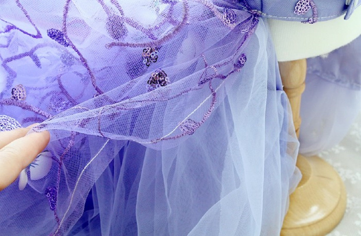 Close-up of a purple dress with floral embellishments on a mannequin.