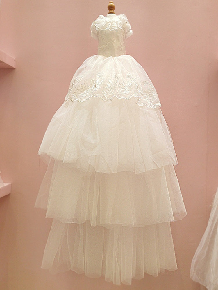 White lace dress on a mannequin against a pink background