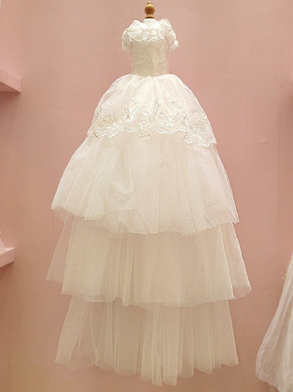 White lace dress on a mannequin against a pink background