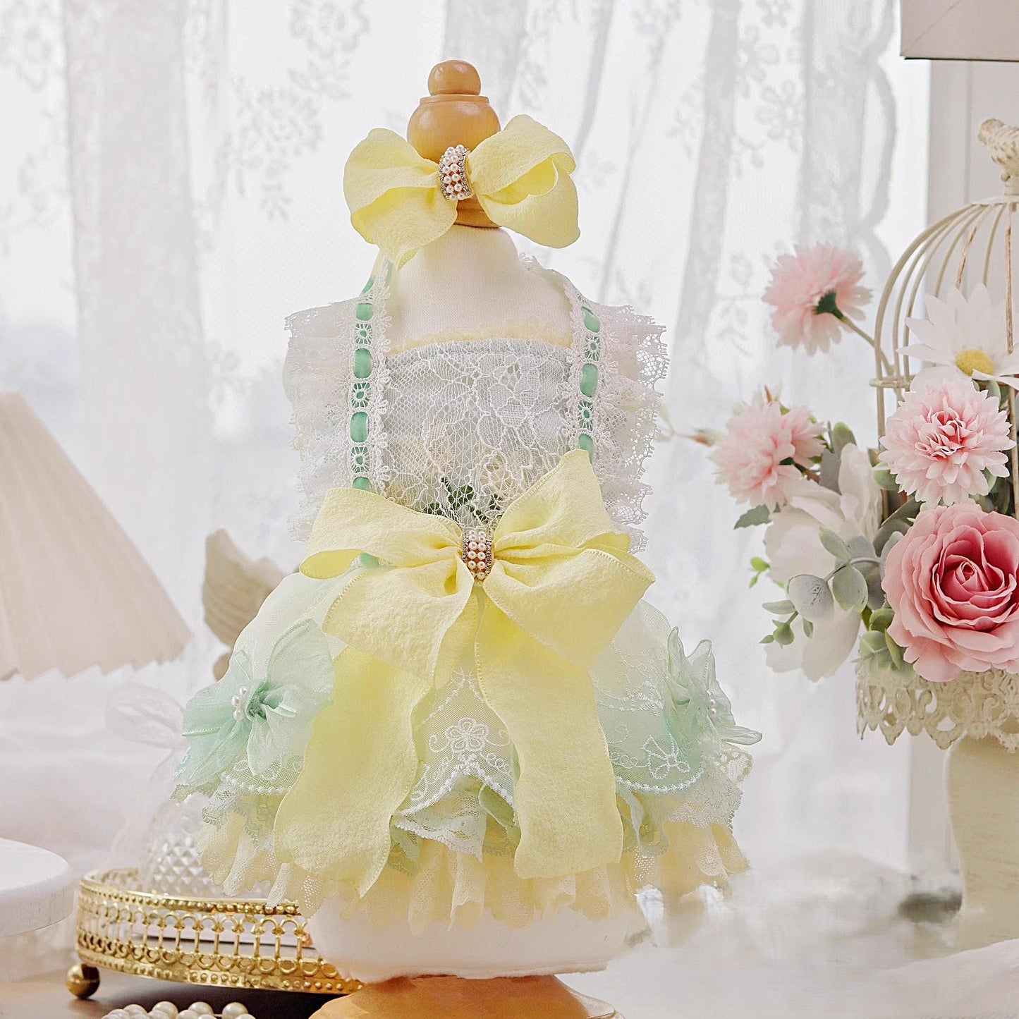 Decorative mannequin with a yellow bow and lace dress in a soft, blurred indoor setting.