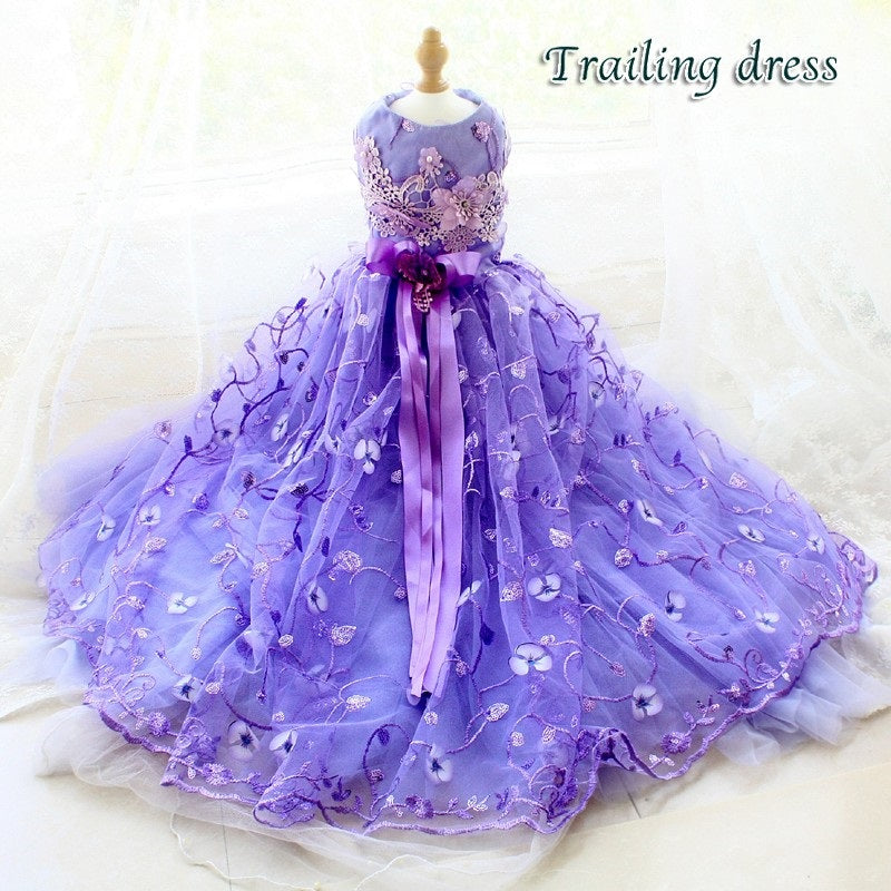 Purple trailing dress on a mannequin with floral details against a white background