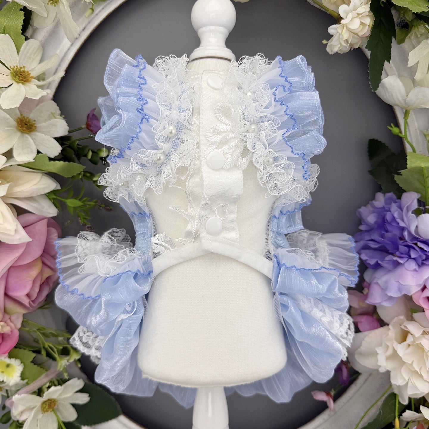 Decorative headband with ruffles on a mannequin head surrounded by flowers