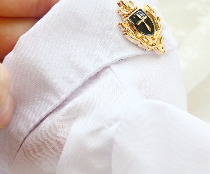 Gold and black decorative pin on a white shirt
