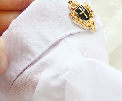 Gold and black decorative pin on a white shirt