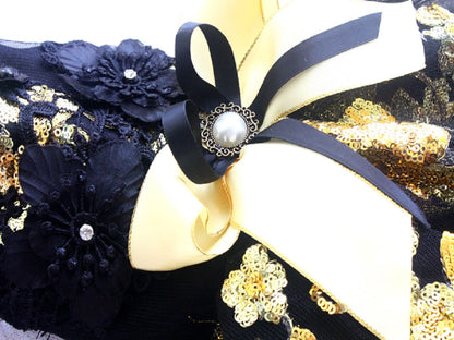 Decorative headband with black and gold flowers and ribbons on a white background