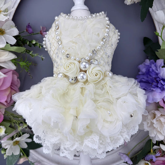Delicate white floral dress with pearls and lace on a mannequin against a floral background