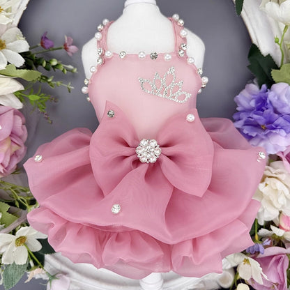 Pink pet dress with decorative elements on a mannequin against a floral background
