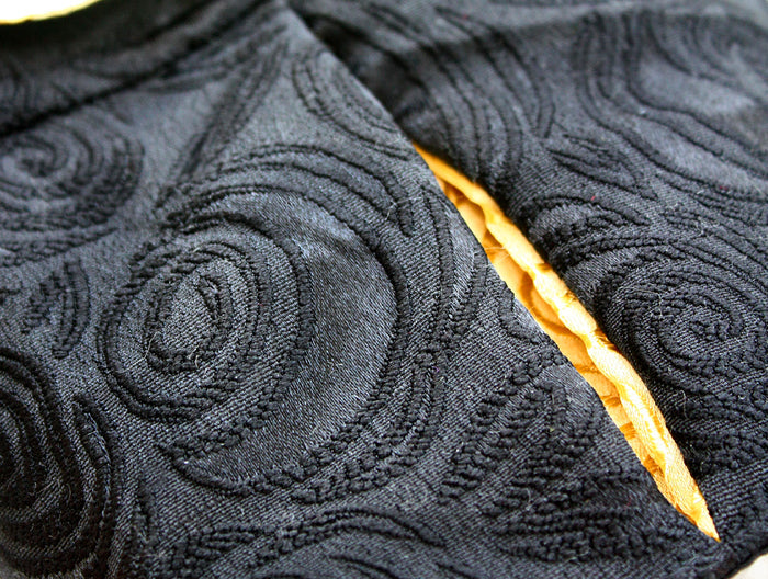 Close-up of textured black fabric with a yellow seam