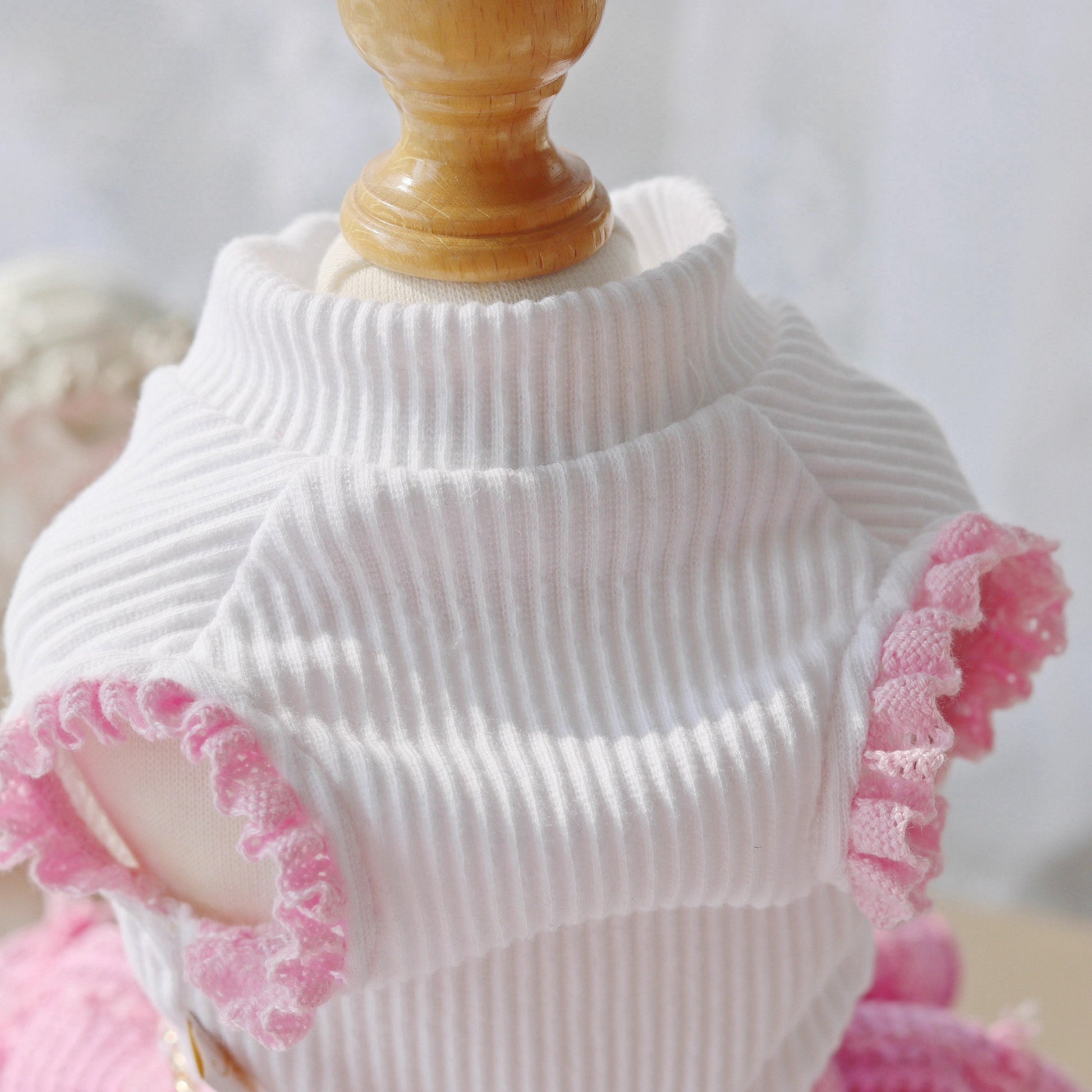 White ribbed sweater with pink lace trim on a mannequin against a white background