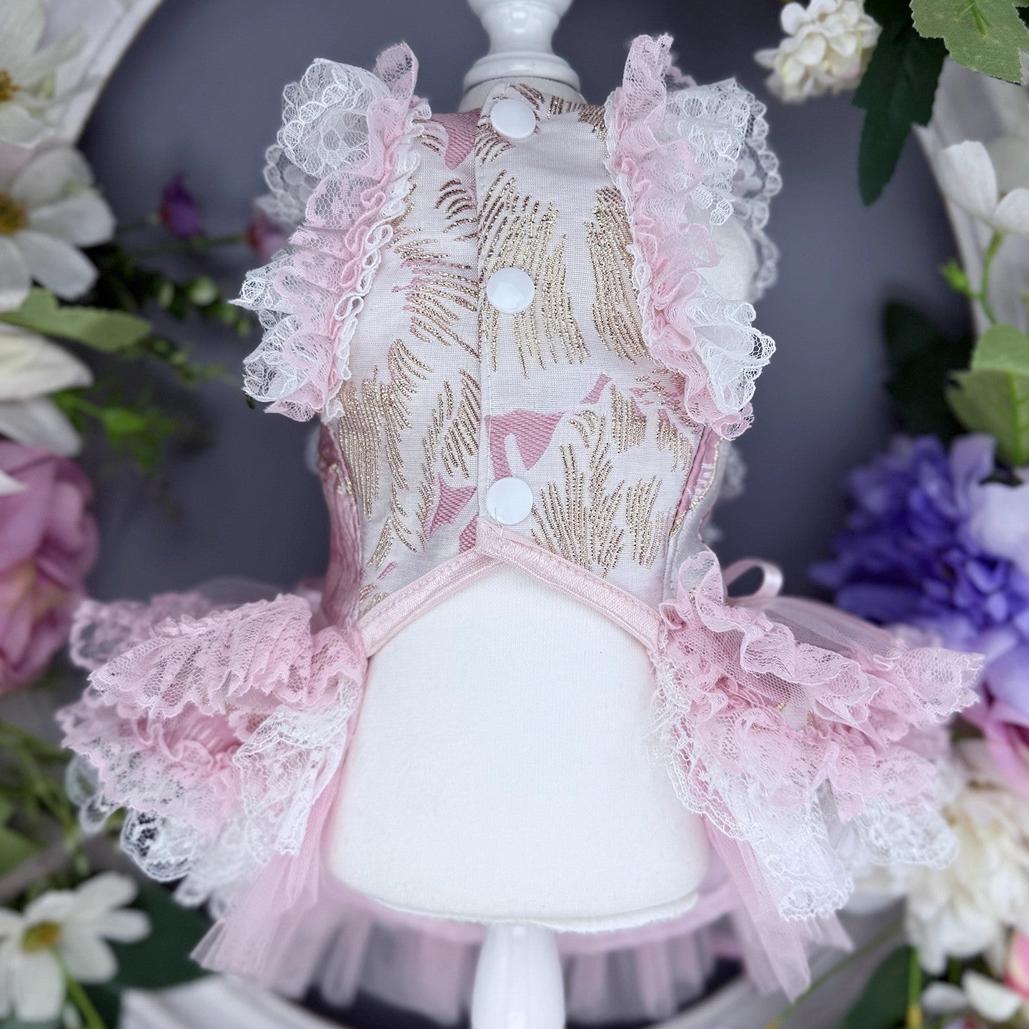 Pink lace dress on a mannequin with floral background