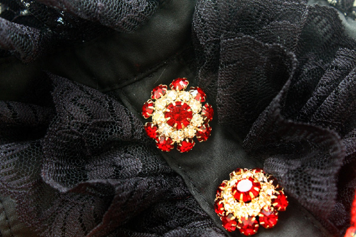 Red and gold floral earrings on a textured black background