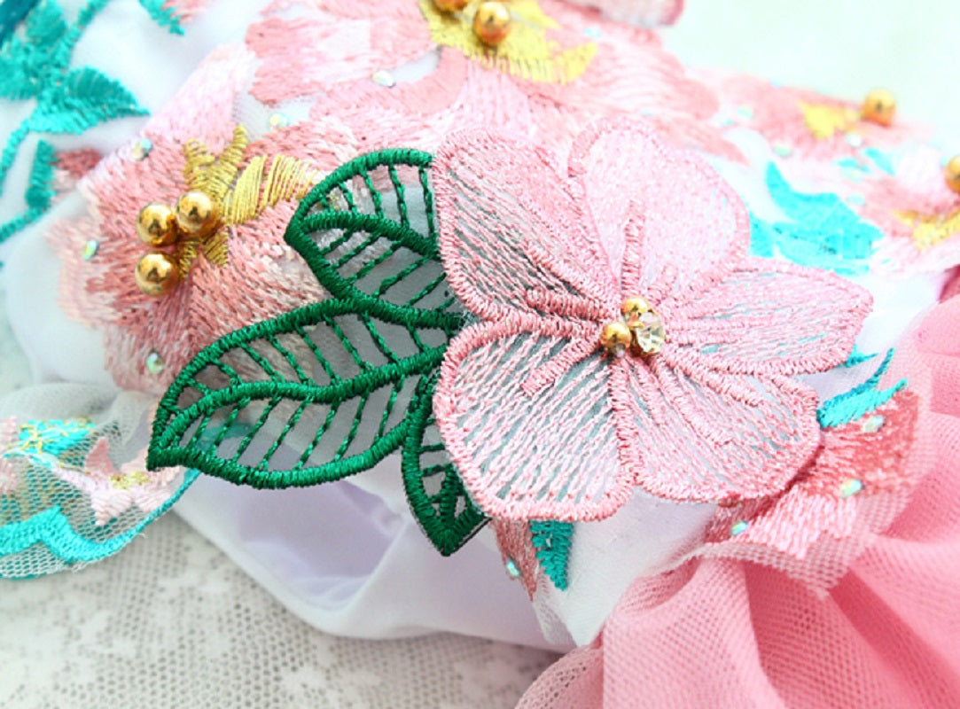 Close-up of decorative floral fabric with pink flowers and green leaves on a white background