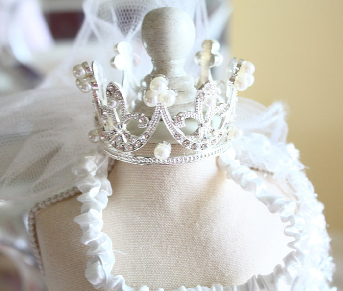 White dress form with a decorative silver crown on a blurred background