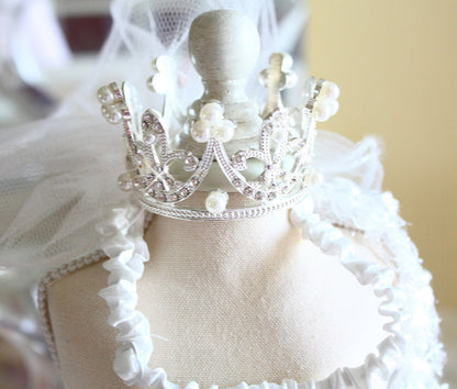 White dress form with a decorative silver crown on a blurred background