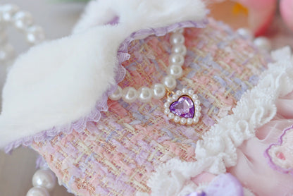 Decorative item with a heart-shaped purple gem and pearl necklace on a textured surface.