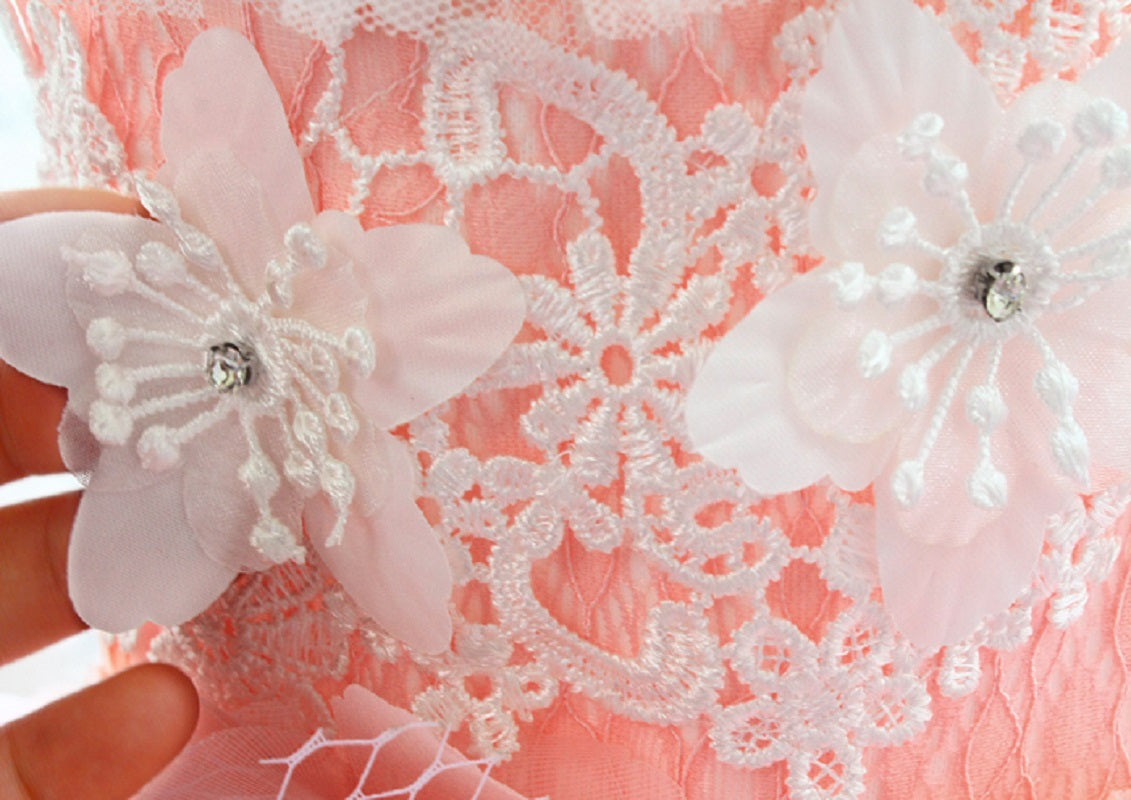 Close-up of pink lace fabric with floral embellishments and rhinestones.