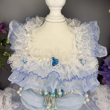 Decorative lace shawl with pearls and blue accents on a mannequin against a dark background.