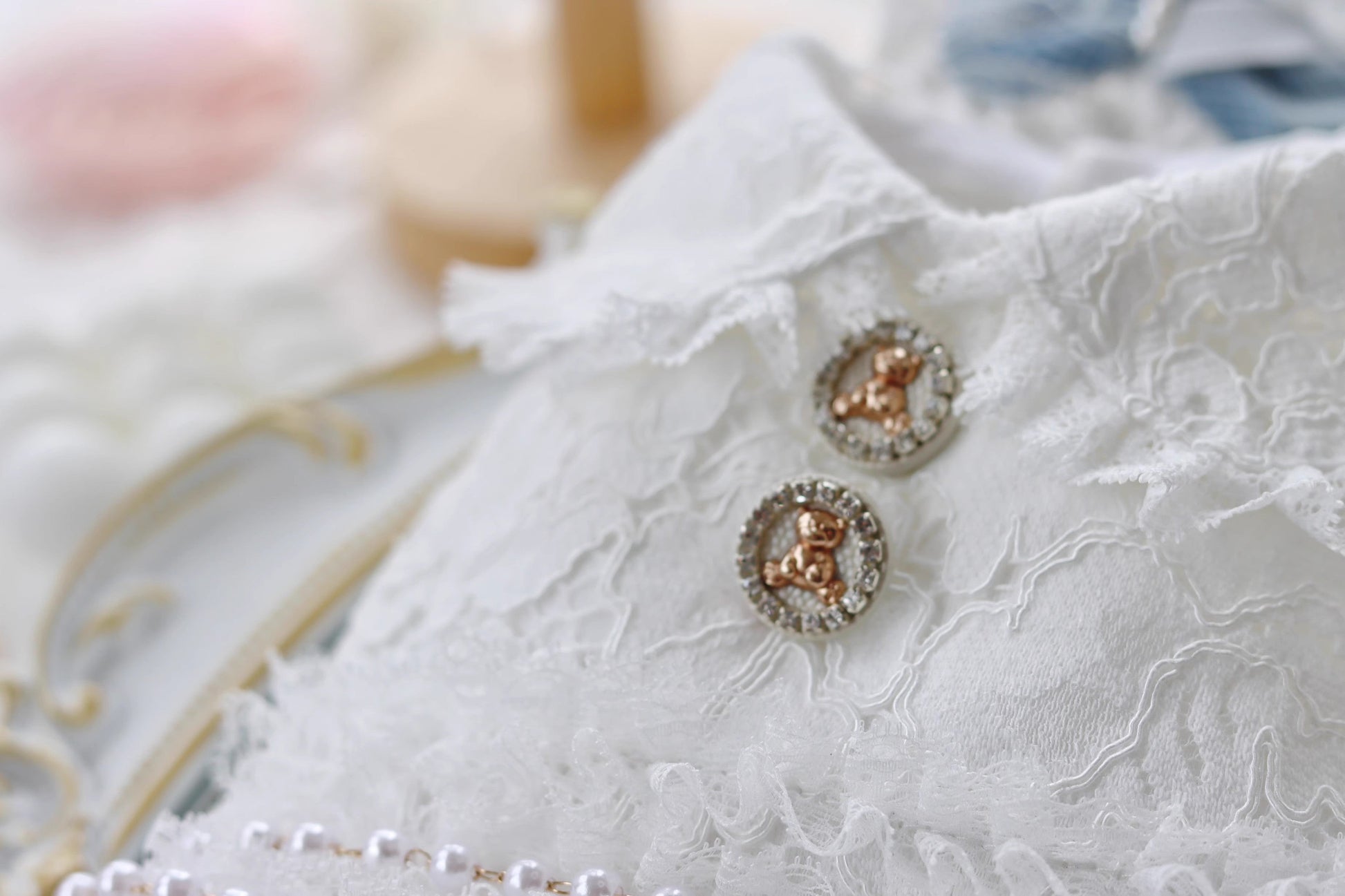 Rose gold earrings on a white lace fabric background