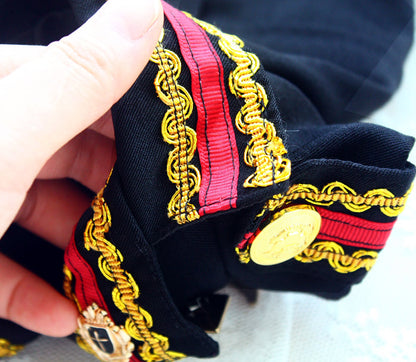 Close-up of decorative ribbon with gold and red details held by a hand.