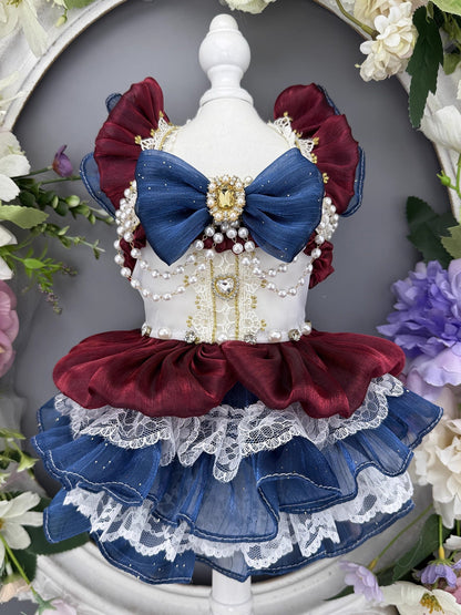 Dog dress with red, blue, and white colors on a decorative stand with flowers in the background